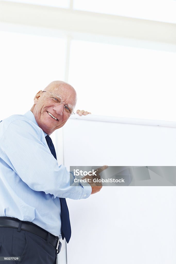 Felice anziano Uomo d'affari che punta alla lavagna bianca in ufficio - Foto stock royalty-free di Abbigliamento da lavoro