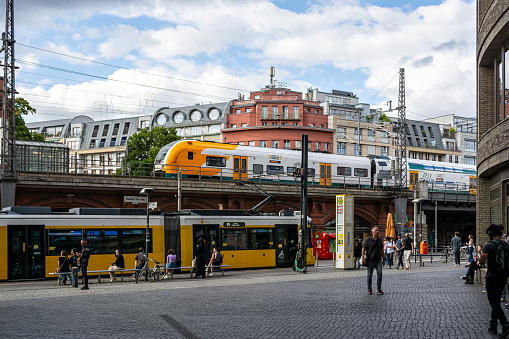 Berlin, Germany, July 20: Cityscape with a yellow tram and high-speed train on a railway overpass in one of the areas in Berlin on July 20, 2023.