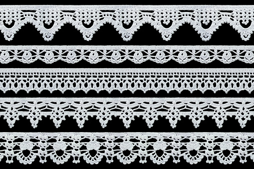 Set of white tape lace on a black background. The lace is crocheted by hand. Vintage style. Material for stylish graphic decoration.