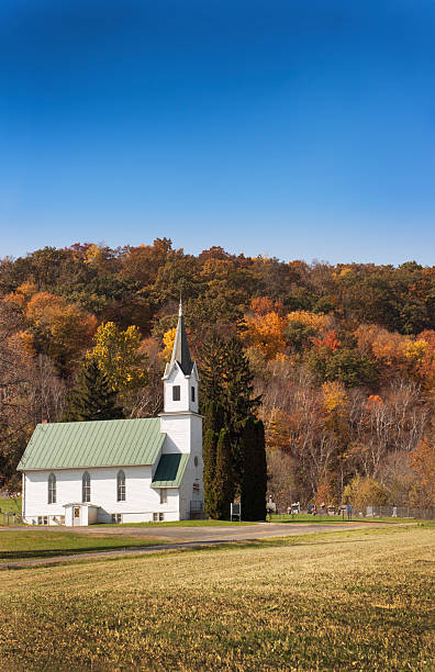 istock Rural White Wooden Steeple Church, Graveyard, Autumn Trees, Blue Sky 183277548