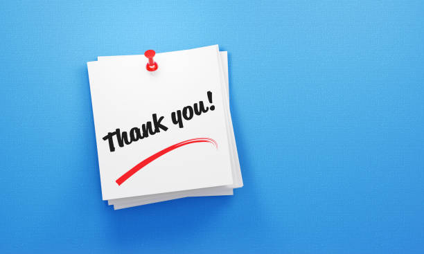 Thank you written post its notes pinned by a red thumbtack on blue background. Horizontal composition with copy space. Reminder concept.