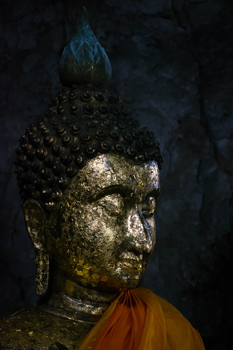 A statue of Buddha with gold inside the cave of a temple in Thailand.
