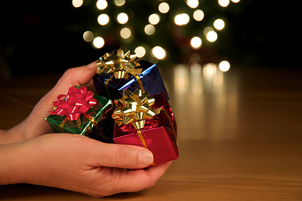 istock Hands Giving Three Christmas Gifts. Blurred Lights. Horizontal. 183278425