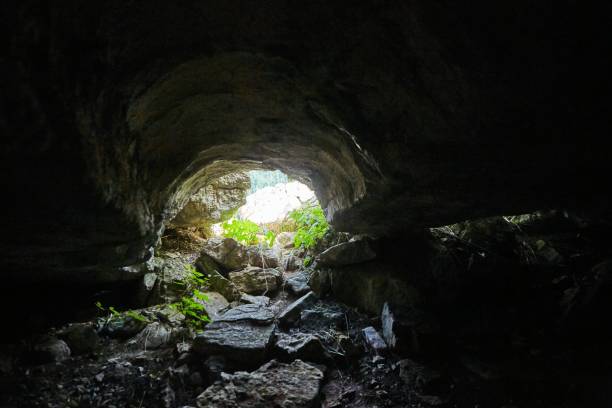 istock Dark cave view from inside with a lumen. Stalactites and stalagmites inside the stone grotto. Colorful stones in the cave. Lighting electricity beauty of the cave. 1832784855