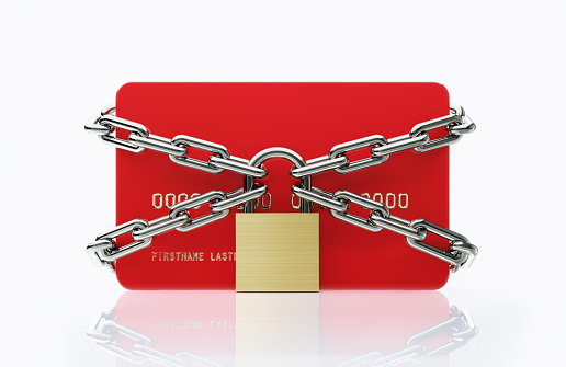 Red credit card chained by padlock and colored chains on white background. Horizontal composition with copy space.
