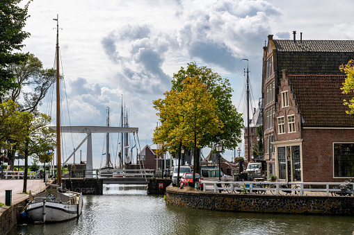 View over Oude Haven canal in Hoorn, The Netherlands in the inner harbor with iron drawbridge Hoge Brug lined with historic buildings and traditional Dutch boats