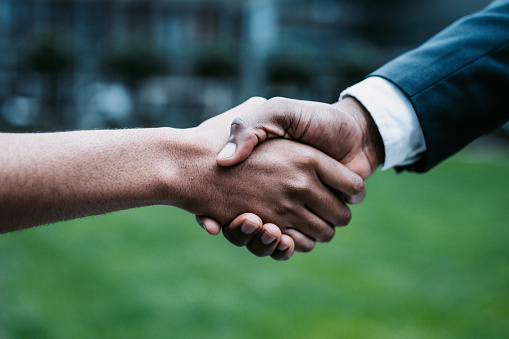 Meeting success. Two business persons shaking hands standing outside