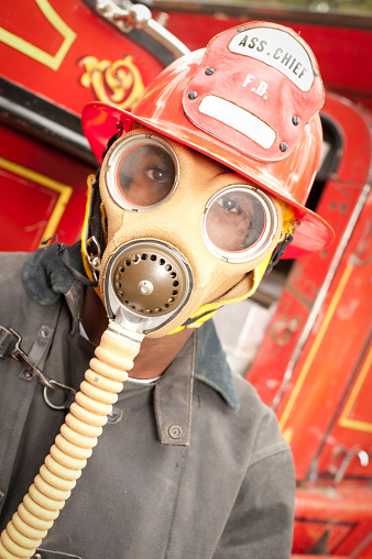 A fireman or firefighter sits on a 1930s antique fire engine truck in authentic pre 1950 clothing and equipment.  Click to view similar images.