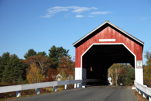 Autumn colors surround the Carleton Covered Bridge in rural New Hampshire. Photo taken during peak fall foliage season in the Monadnock region near Keene. New Hampshire is one of New England's most popular fall foliage destinations bringing out some of  the best foliage in the United States