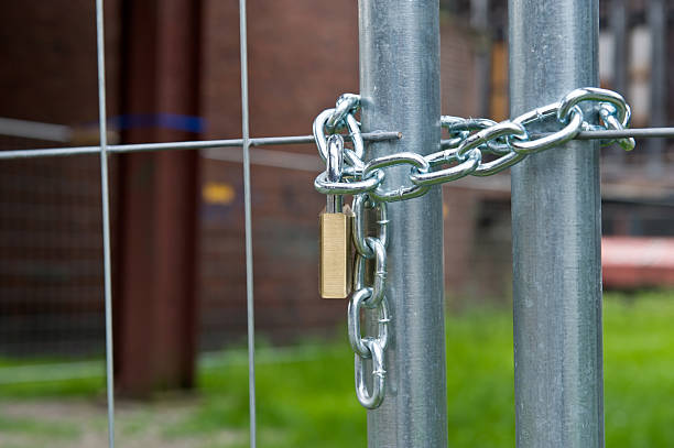 Pad lock locking chain link fence - Locked gate stock photo