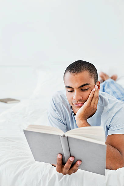 istock Young Man Reading a Book on the Bed 183281952
