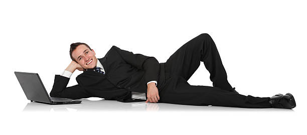 Businessman reclining beside laptop Businessman reclining beside laptophttp://www.twodozendesign.info/i/1.png lying on side stock pictures, royalty-free photos & images