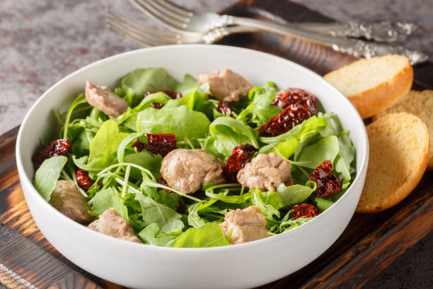 istock Delicious cod liver salad with arugula and sun-dried tomatoes served with toast close-up in a bowl. Horizontal 1832825680