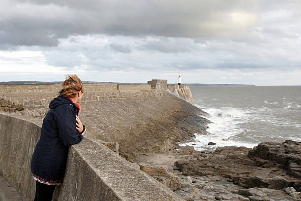 istock Mature windswept woman at sea wall 183282592