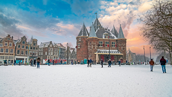 Traditional snowy Waag building at the Nieuwmarkt in Amsterdam in the Netherlands in winter at sunset