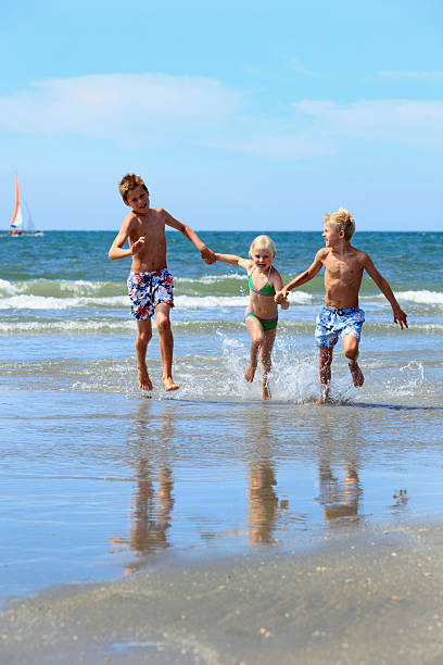 istock three children running in the sea 183282739
