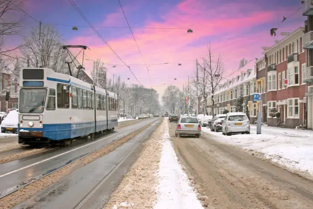 Tram driving in snowy Amsterdam in the Netherlands at sunset