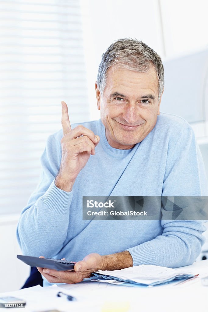 Old man with calculator and bills pointing at copy space Smart senior man with calculator and bills while pointing at copy space Counting Stock Photo