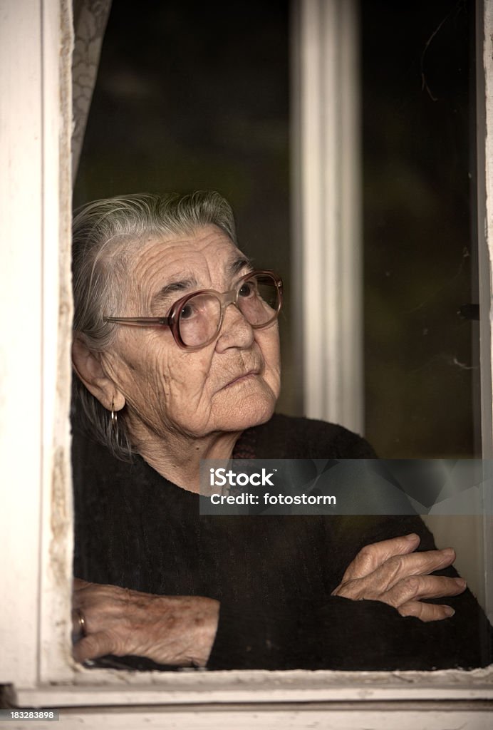 高齢者の女性の窓のそばに立つと外 - 悲しみのロイヤリティフリーストックフォト