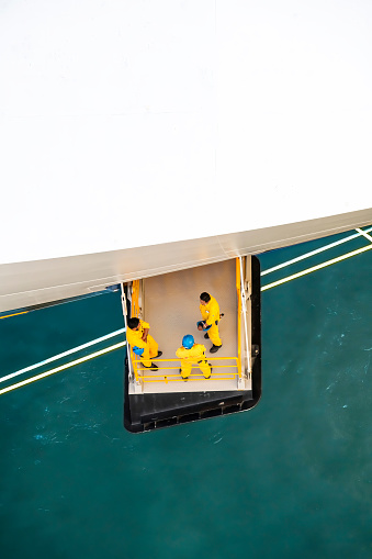 Rotterdam, the Netherlands-August 20, 2023; Bird’s eye view of hatch or small vertical doors or diving board on the bow and above the anchor of a cruiseship with several staff members on the platform