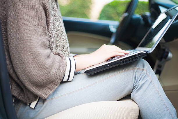 woman typing on laptop in a car