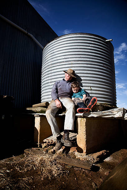 Sleeping farmer and grandson Hardworking Australian farmer having a afternoon nap with his grandson. Desaturated and high contrast. sleeping grandpa stock pictures, royalty-free photos & images