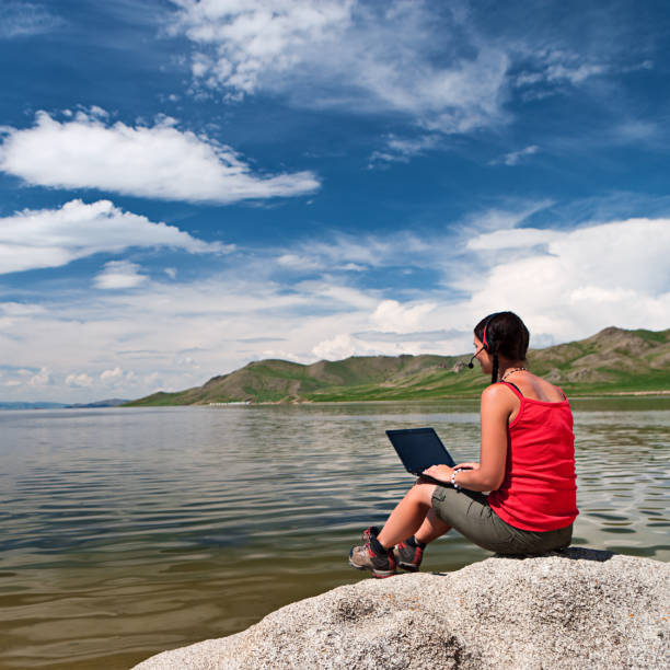 Young woman with laptop on the rock