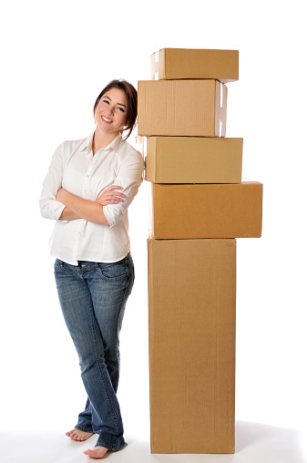 Vertical image of beautiful woman leaning on a stack of  boxes. 