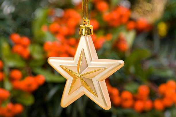 Golden Star Bauble in Front of Christmas Decoration stock photo