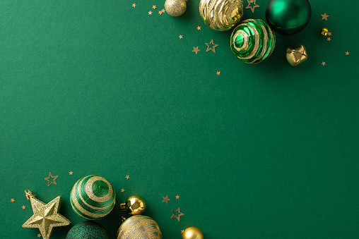 Sumptuous New Year scene. Top view shot capturing opulent ornaments, glittering star decoration, jingle bells, and gold confetti arranged on a green backdrop, with space for promotional text