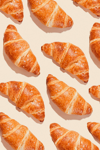 Pattern, background of croissants on a light background with sharp shadows