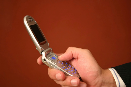 Close-up side view of businessman's arms/hands making a call on cell phone.