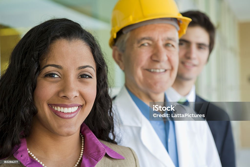 Sorrindo homem sênior usando capacete de negócios com duas pessoas - Foto de stock de 20 Anos royalty-free