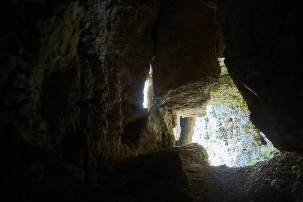 istock Dark cave view from inside with a lumen. Stalactites and stalagmites inside the stone grotto. Colorful stones in the cave. Lighting electricity beauty of the cave. 1832867825