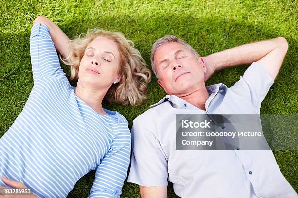 Tranquila Mujer Madura Con Hombre Juntos Lying On The Grass Foto de stock y más banco de imágenes de Acostado