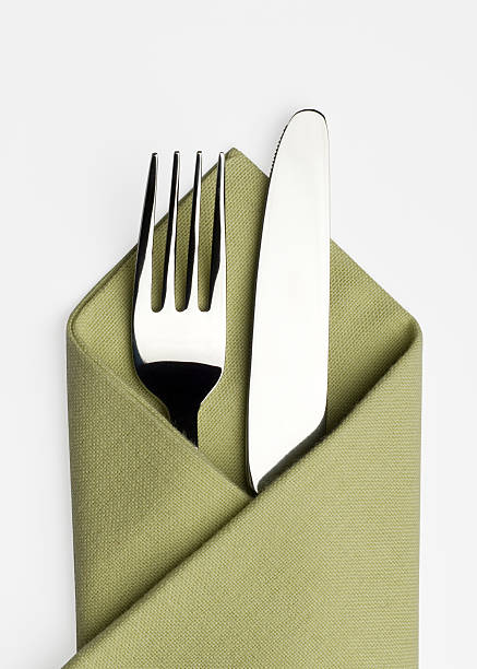 Knife and fork in a green napkin A studio shot of a knife and fork placed in a green serviette on a white background with Clipping Path and shadows napkin stock pictures, royalty-free photos & images