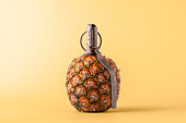 Creative fruit concept. Pineapple shaped pomegranate with fuse on yellow background.