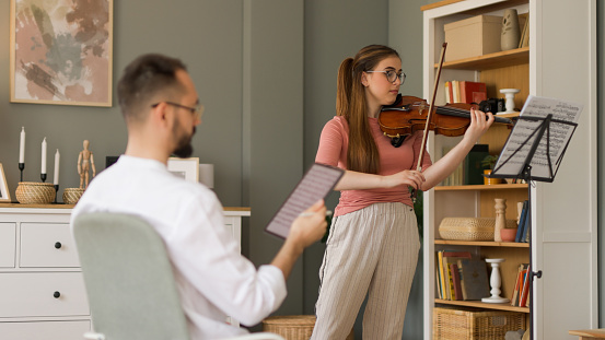 Male music teacher giving private violin lessons to a teenage girl
