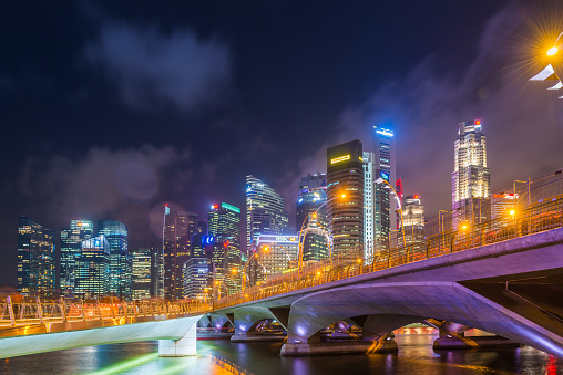 The glittering lights of Downtown Core skyscrapers reflecting in the tranquil waters of Marina Bay at night in the heart of Singapore.