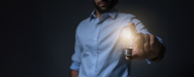 Businessman holding light bulb. Idea concept with innovation and inspiration. businessman holding illuminated light bulb. Brain creative thinking ideas and innovation concept.