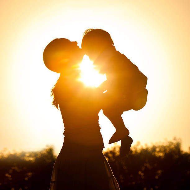Mother and her child hugging at sunset outdoors.