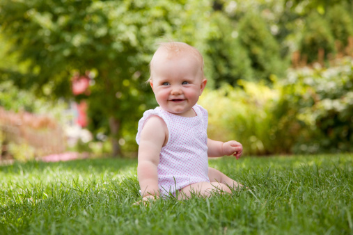 8 month old baby girl sitting on grass in a park in the summer timeClick for more baby pictures: