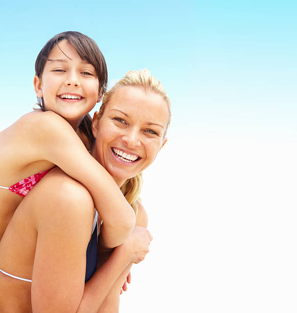 Happy mother giving daughter piggyback ride