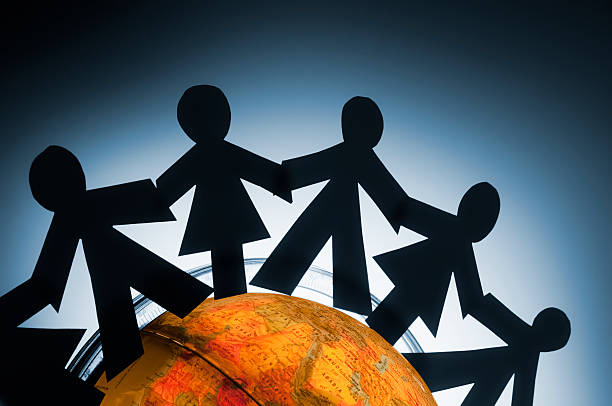 istock Paperchain people holding hands around a globe 183290804
