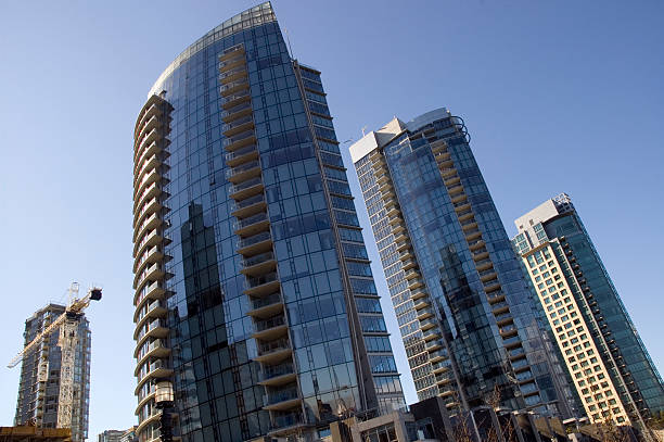 Three modern apartment buildings "Photo of a three slender apartment towers in the bright Spring sun.The three brand new condo towers are located in Coal Harbour on Vancouver's waterfront, facing the North shore mountains. Magnifiscent views for these overpriced glass cages." false creek stock pictures, royalty-free photos & images