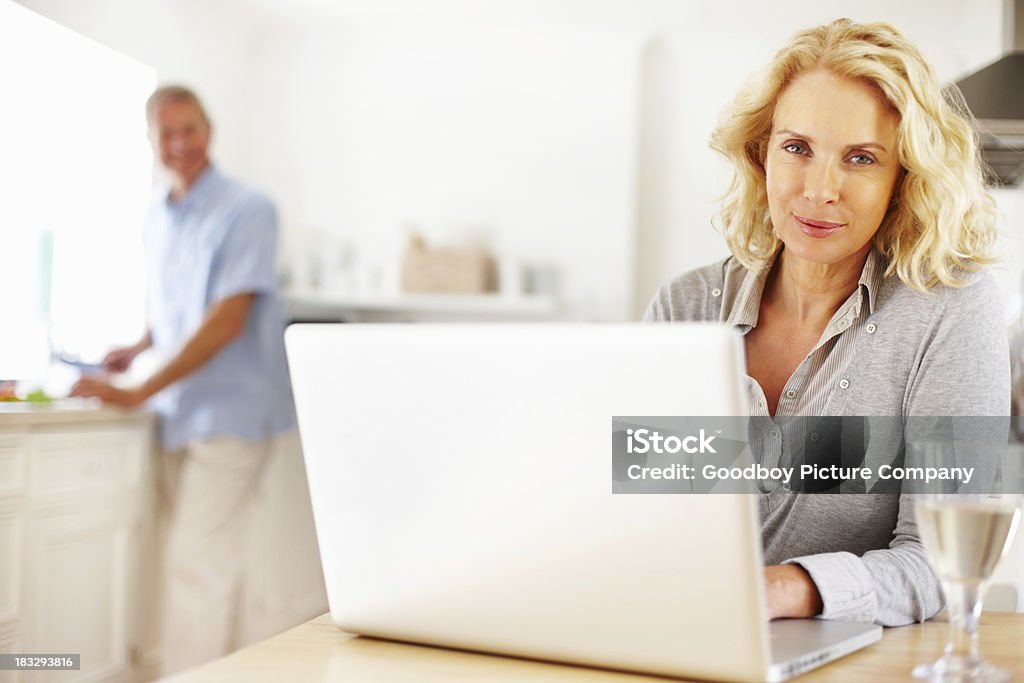 Mulher usando laptop com borrão homem a cortar vegetais - Royalty-free 40-49 Anos Foto de stock