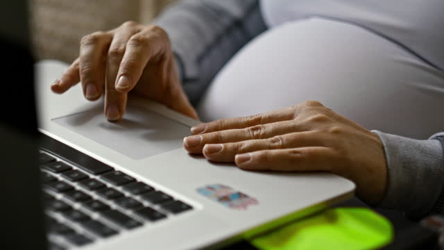 Close up hands of pregnant woman using laptop