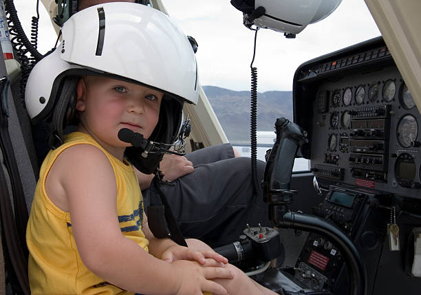 A serious young boy with his dad's helmet on sitting at the controls of a helicopter.  Click on an image to go to my Helicopters Lightbox