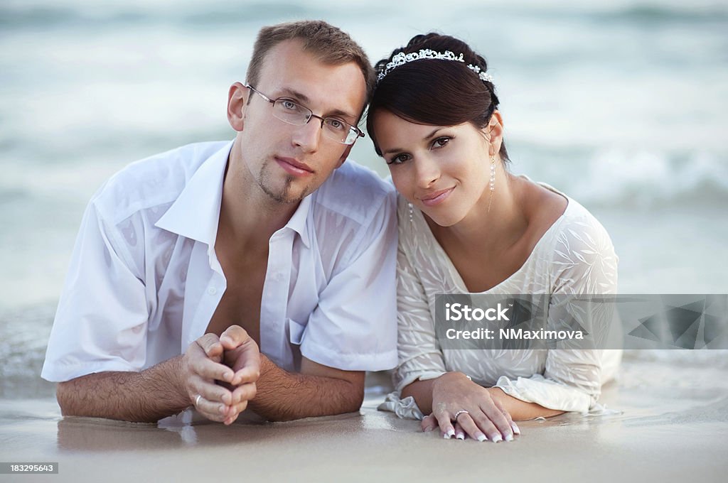 Le marié et la mariée allongé sur la plage. - Photo de Adulte libre de droits