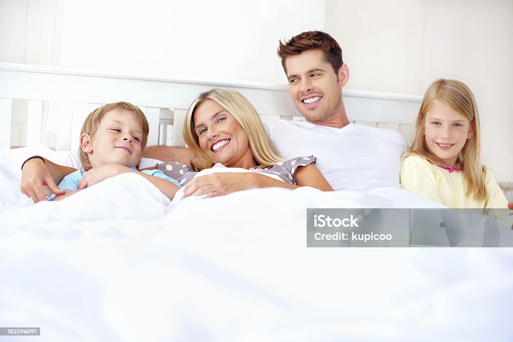 Szczęśliwa średnim wieku Para z ich dzieci leżąc w łóżku - Zbiór zdjęć royalty-free (20-29 lat)